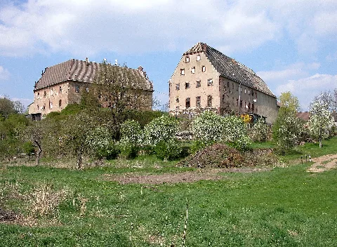 22.04.2005 04886 Kössern (Grimma), Zum Rittergut 9: Das Rittergut (nicht zu verwechseln mit dem Jagdhaus) nimmt ein erhöhtes Terrain am Ufer der Mulde ein. Das Herrenhaus (GMP: 51.179094,12.784131) besteht aus zwei rechtwinklig angeordneten Flügeln. In den Giebel des Hofflügels ist das Wappen der Familie von Erdmannsdorff mit der Jahreszahl 1695 eingelassen. Die letzte Umgestaltung erfolgte 1894. Dabei wurden die Giebelfronten mit einer reichen Dekoration im Neorenaissancestil versehen. Im hofseitigen Giebel kann man die Inschrift "A. v. A. / 1894" lesen. Das Monogramm bezieht sich auf Alfred von Abendroth, einen Nachfahren des Kaufmanns Christian Friedrich Abendroth (1744-1811), der das Rittergut 1772 von Friedrich Wilhelm von Erdmannsdorff erworben hatte. In der DDR-Zeit waren im Haus Kindergarten/-krippe und Wohnungen. Derzeit desolater Zustand, Mietwohnungen. Sicht von der Mulde. [DSCN6484.TIF]20050422130DR.JPG(c)Blobelt