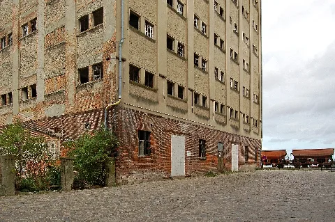 Leerstehendes Lagerhaus im Industriehafen. Am Stadthafen legen die Fährschiffe nach Hiddensee und Altefähr sowie zu diversen Hafenrundfahrten an. Der Hafen ist im Sommer auch Liegeplatz für Flusskreuzfahrtschiffe. In den Jachthäfen und Marinas im altstadtnahen Bereich ankern auch die Skipper mit ihren Segelbooten. Auch entlang der Nordmole machen im Sommer oft hunderte Jachten und Segelboote fest. Das »Lotsenhaus« und die Hafenspeicher sowie die Silhouette der Altstadt bieten einen ansprechenden Kontrast zur Aussicht auf die Inseln Rügen und Hiddensee. Eine weitere touristische Attraktiion liegt mit der Bark »Gorch Fock« im Hafen. Ein weiteres Highlight ist das am 11. Juli 2008 eröffnete Meeresmuseum »Ozeaneum«. Natürlich gibt es hier auch weniger schöne »Hafenansichten«, wie leer stehende, runtergekommene Gebäude, ganz einfach wie in jedem anderen Hafengebiet einer Stadt auch. Gehört aber einfach auch dazu.