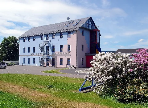 02.06.2015 09526 Olbernhau, Am Alten Gaswerk: Ehemaliges Gas- und E-Werk Olbernhau (GMP: 50.663415,13.324246). Die Gebrüder Karl Einhorn und Wilhelm Einhorn haben in Olbernhau auf der Blumenauer Straße das erste Elektrizitätswerk im Königreich Sachsen errichtet. Am 05.07.1892 wurde es eröffnet und am 18.10.1892 lieferte das Werk schon den ersten Strom ins Netz. 1939 übernimmt die "AG Sächsische Werke" die Gas- und Elektrizitätsversorgung in Olbernhau. 1948 kam es zur Gründung der "Vereinigung Volkseigener Betriebe (VVB) - Energiebezirk Ost). Das Gaswerk lieferte bis zur Inbetriebnahme einer Ferngasleitung im Jahr 1972 noch Stadtgas. Danach wurden die Anlagen teilweise abgerissen oder zu Produktionsräumen umgebaut. Heute sind die Stadtwerke Olbernhau GmbH ein ortsansässiges Energieversorgungsunternehmen und 100%ige Tochtergesellschaft der Stadt Olbernhau mit den Geschäftsräumen im Haus Am Alten Gaswerk 1. Am Firmensitz nimmt die Galerie Am Alten Gaswerk einen etablierten Platz ein. [SAM0671.JPG]20150602245DR.JPG(c)Blobelt