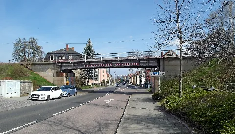 10.04.2023 01189 Dresden-Gittersee: Brücke der Windbergbahn (GMP: 51.008620,13.691310) über die Karlsruher Straße. Die heutige Karlsruher Straße verbindet die Stadtteile Coschütz und Gittersee mit Plauen und ist zugleich wichtige Verkehrsverbindung nach Freital. Nachdem in Gittersee um 1810 Steinkohlevorkommen entdeckt worden waren, wuchs die Bedeutung dieses Verkehrsweges, der zwischen 1841 und 1844 zur Chaussee ausgebaut wurde. Ab 1855 überquerte eine Steinbogenbrücke der Windbergbahn die Straße. Nach dem Zweiten Weltkrieg wurde sie 1965 durch eine Stahlträgerbrücke ersetzt. Die Steilstrecke der auch als "Sächsische Semmeringbahn (R)" bekannten ersten deutschen Gebirgsbahn von der Talstation Freital-Birkigt nach Dresden-Gittersee ist eine große technische Meisterleistung des Eisenbahn- und Vermessungswesens ihrer Zeit. Die Strecke wurde in den Jahren 1855/56 nach den Plänen von Oberingeneuer Guido Brescius als Kohlenbahn projektiert und gebaut. Der Bahnhof Gittersee wurde im Jahre 1907 von den Königlich Sächsischen Staatseisenbahnen (K.Sächs.Sts.E.B.) [auch: K.S.S.E.B.] für den allgemeinen Güter- und Personenverkehr ausgebaut. Im Jahr 1957 wurde der öffentliche Personenverkehr und 1993 der Güterverkehr eingestellt. [SAM6321.JPG]20230410110DR.JPG(c)Blobelt