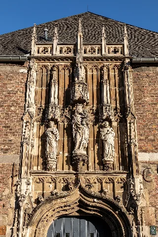 Entrance (overdoor statues: Saint John the baptist, Madonna with Child, Saint Joseph) of the Cathedral Treasury in Aachen, North Rhine-Westphalia, Germany