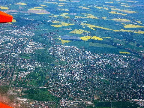 original Bildbeschreibung: Abflug nach Teneriffa über Berlin. erweiterte Beschreibung: Die Position des Flugzeugs könnte inetwa über Biesdorf-Süd sein. Damit fängt der Sichtbereich unten links an. Der Blick geht über den Wuhleverlauf / das Wuhletal, Kaulsdorf, Hellersdorf, bis nach Barnim hinein. Dort ist als markantestes, der Solarpark Eiche zu sehen, demzufolge links davon Eiche, weiter rechts Mehrow und noch weiter hoch dann Blumberg. Links ziemlich oben im Bild, am Anfang der Wuhle ist Ahrensfelde zu sehen und unterhalb dann Teile von Marzahn. Auf mittlerer Bildhöhe, ist am Wuhleverlauf, über dem Wuhleteich, der Kienberg und etwas Höher, die Ahrensfelder Berge zu sehen. Durch den Blickwinkel fallen sie als Berge aber nicht auf und sehen eher nur nach einer Waldfläche aus. Rechts über Hellersdorf, also etwas über der mittleren Bildhöhe, ist das zu Hoppegarten gehörende Dorf Hönow mit See zu sehen und von dort nach links rüber zum Solarpark Eiche das Waldstück Herrendike. Ganz unten verläuft quer die B1 und etwas darüber ist eine ebenso quer verlaufende S-Bahnstrecke mit den Bahnhöfen Wuhletal, Kaulsdorf und Mahlsdorf zu sehen. Die hier als GEO Daten angegebene Kameraposition zeugt einen Punkt etwas rechts von der Bildmitte auf dem Feld, aber nicht die Kameraposition.