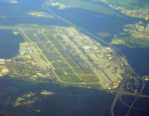 Aerial photo looking from the east showing Frankfurt airport as a light island in the dark forest. Service areas, passenger and cargo terminals to the right, to the left the former US Air Base, where among others "Cargo City South" is being built.