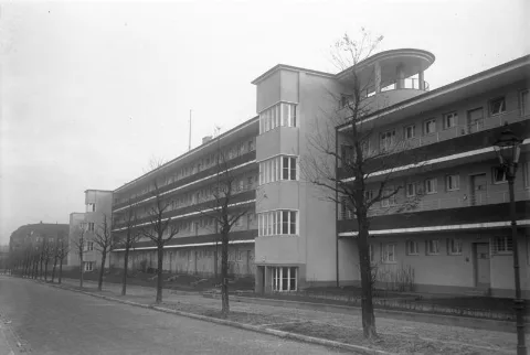 For documentary purposes the German Federal Archive often retained the original image captions, which may be erroneous, biased, obsolete or politically extreme. Das erste Laubenganghaus in Berlin-Steglitz! Dieses eigenartige Haus ist an der Aussenfront mit Laubengängen versehen, von welchem aus die einzelnen Wohnungen betreteten werden. Der grosse Vorzug dieser Bauart liegt darin, dass man die nicht immer einwandfrei gelüfteten Mietstreppenhäuser durch einen luftigen sonnigen Gang ersetzt hat. Ausserdem geniesst der einzelne Mieter die Behaglichkeit des Einfamilienhauses. Im Obergeschoss sind zwei grosse Luft- und Sonnenbäder für die Mieter vorhanden. Standort: Neuchateller Straße, 12203 Berlin