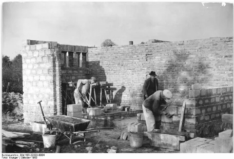 For documentary purposes the German Federal Archive often retained the original image captions, which may be erroneous, biased, obsolete or politically extreme. ADN-Zentralbild-Krueger, 28.10.1953 Volkseigenes landwirtschaftliches Kombinat im Kreis Löbau. Neun volkseigene Güter im Kreis Löbau, Bezirk Dresden, wurden zu dem grossen Kombinat Bertelsdorf-Groß-Schweidnitz zusammengelegt mit einer landwirtschaftlichen Nutzfläche von 1300 Hektar. Die einzelnen landwirtschaftlichen Arbeiten führen 9 Feldbaubrigaden, 9 Tierzuchtbrigaden und zwei Traktorenbrigaden durch. UBz.: Drei Zweifamilienhäuser für die Arbeiter des zum Kombinat gehörenden Volksgutes Löbau werden von der privaten Baufirma Vetter in der Ostsiedlung von Löbau gebaut. Das Geld für den Bau von Wohnungen für die Landarbeiter wurde in Verwirklichung des neuen Kurses bereitgestellt.