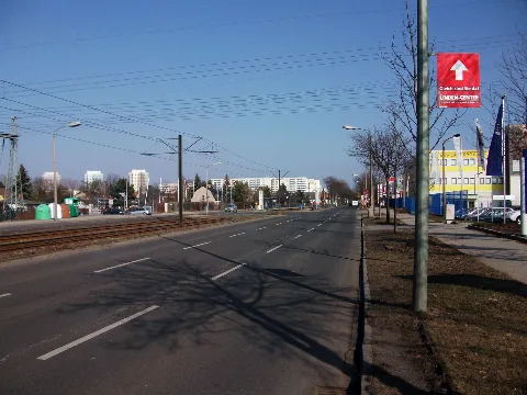 Hansastraße in Berlin-Alt-Hohenschönhausen, Blick nord-östlich Richtung stadtauswärts. Der Standort ist vor einem größeren Autohändler-Gelände mit den Hausnummern 212 und 214. Links ist am Bildrand angeschnitten eine Hochspannungsmasttraverse vom Umspannwerk mit der Hausnummer 213, an der Ecke zur Feldtmannstraße zu sehen, davor stehen Altglas- und ein Kleidersammelkontainer. Geradezu befindet sich hinter dem Kreuzungsbereich zur Feldtmannstraße die nach ihr benannte Straßenbahnhaltestelle. Rechts das Gebäude mit den gelben Streifen ist die Nr. 216 mit einem Lagerflächenanbieter und kleineren Gewerben. Im Hintergrund die Hochhäuser stehen an der Zingster Straße, es sind die Nummern 23, 21 und 15. Rechts der 11-geschossige Wohnblock steht an einem Ast der Falkenberger Chaussee und hat die Nummern 1-7. An der Straße stehen hier noch mehrere der alten DDR Laternen mit den tropfenförmigen Leuchten vom VEB Leuchtenbau Leipzig. Direkt vor dem Standort steht eine schon erneuerte Laterne mit der Werbung für das Einkaufzentrum Linden-Center an der Ecke von Falkenberger Chaussee zur Zingster Straße. Die Falkenberger Chaussee ist die Weiterführung der Hansastraße nach der Kreuzung zu Darßer Straße und Malchower Weg.