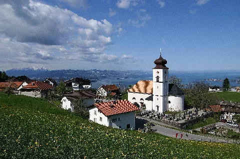 Overlooking the St. Bernard Parish Church at Eichenberg (Vorarlberg), of Lake Constance and the Swiss mountains of Alpstein. Right in the picture: Lindau.