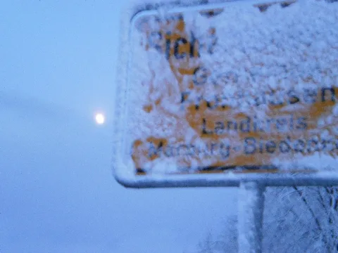 First snow in November on 2015-11-22, at the village Sichertshausen (Fronhausen), Germany, with snow on the surface of sign Zeichen 310 (angewehter Schnee auf der Ortstafel).