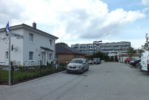 Straße in Berlin-Hohenschönhausen, Olympiaviertel (diese Namensgebung bezieht sich darauf, das man in der Siedlung die Straßen nach Sportlern und dabei auch Olympiateilnehmern benannt hat). In der Joachim-Böhmer-Straße an der Kreuzung zur Erich-Hagen-Straße. Geradezu ist ein altes Bürogebäude eines früheren DDR Betriebes (Wartenberger Straße 40, 1995 bis 2008 Amtsgericht Hohenschönhausen 2009 bis 2012 Amtsgericht Lichtenberg Zweigstelle Hohenschönhausen) zu sehen. Dieses Gebäude (mit weiteren dort) wurde mittlerweile abgerissen und dort ein Wohnblockkarree mit geschlossenem Innenhof errichtet. Diese Siedlung entstand nach 2013 auf dem ehemaligen DDR Betriebsgelände des VEB Spezialhochbau Berlin.