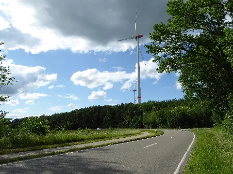 Die Bundesstraße 39 beim Wanderparkplatz Enzwiese (Zufahrt rechts hinten sichtbar) im Grenzgebiet von Löwenstein und Bretzfeld. Links das Naturschutzgebiet Enzwiese, im Hintergrund zwei neu errichtete Windkraftanlagen auf dem Gebiet von Bretzfeld-Unterheimbach (vorne) und Obersulm-Weiler (hinten).