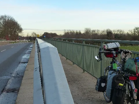 Brücke der Kreisstraße 8 von Loop nach NMS-Einfeld über die A 7. Im Verlauf des benutzungspflichtigen Kombi-Radwegs (Zeichen 240) und von der letzten Verbindung zwischen Fahrbahn und Radweg noch nicht zu erkennen, ist der Weg auf der Brücke als Gehweg ausgeschildert (Zeichen 239), obwohl das Geländer eine ausreichende Höhe für einen Radweg hat. Dass der Zusatz "Radfahrer frei" fehlt, drückt die behördliche Missachtung, ja Bestrafung für diejenigen Bürger aus, die ihre Mobilität umwelt- und mitbürgerverträglich bewältigen.