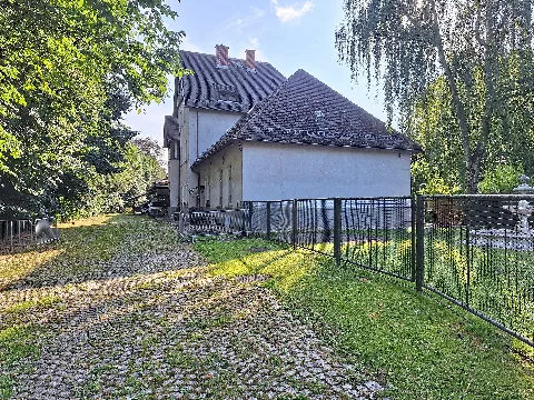 Former station building of Münchenbernsdorf railway station in Münchenbernsdorf, Greiz district, Thuringia, Germany. The photograph shows the courtyard and access side of the former station building with its attached goods shed. The station was the terminus of the Niederpöllnitz–Münchenbernsdorf branch line. The goods shed was enlarged several times to accommodate freight traffic generated by the town's carpet industry. Since the closure of the railway line in 1995, the building has been used for other purposes.