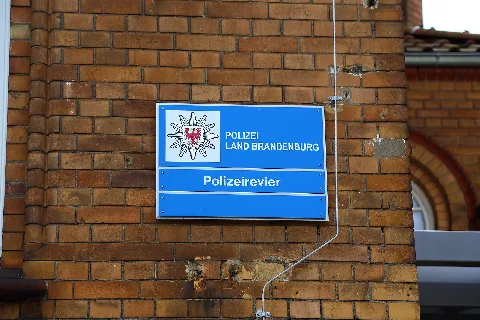 Sign at the police station (Polizeiwache) in Lübben, Landkreis Dahme-Spreewald, Brandenburg, Germany. It is the psychiatric hospital's former administration building and situated on the corner of Luckau Street (Luckauer Straße) and Station Street (Bahnhofstraße).