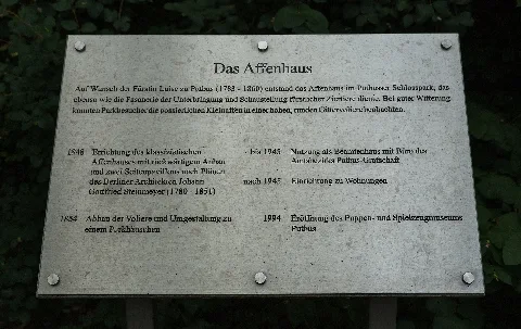 Information plaque at the former monkey house (Affenhaus) at Putbus Palace Park in Putbus, Landkreis Vorpommern-Rügen, Mecklenburg-Vorpommern, Germany. Since 1994 the building, a listed cultural heritage monument, houses the toy museum Rügener Puppen- und Spielzeugmuseum Putbus and also serves as a café.