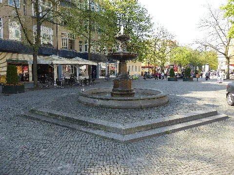 Schalenbrunnen (so genannter Schinkelbrunnen) Der Brunnen stand ursprünglich im ehemaligen Studentenpark Hardenbergstraße (heute Hochschule der Künste). Der Abriss dort erfolgte 1954, die Wiederaufstellung nach Restaurierung 1976 in der Fußgängerzone Alt-Tegel. Ein rundes Natursteinbecken steht auf einem stufenförmigen sechseckigen Podest. In seiner Mitte erhebt sich eine verzierte Brunnensäule, die übereinander zwei unterschiedlich große Schalen trägt. Aus einer kleinen Fontäne fällt Wasser in die obere kleine Schale, über deren Rand hinaus in die untere große und von dort in das Becken. Die Brunnenanlage ist ein beliebter Treffpunkt.