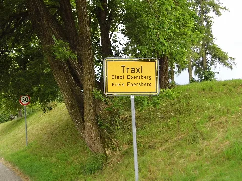 Traxl (Stadt Ebersberg, Kreis Ebersberg), Ortseinfahrt von Norden, 28. Juni 2020; gelbe Ortstafel "Zeichen 310" in Landkreis Ebersberg, Oberbayern.