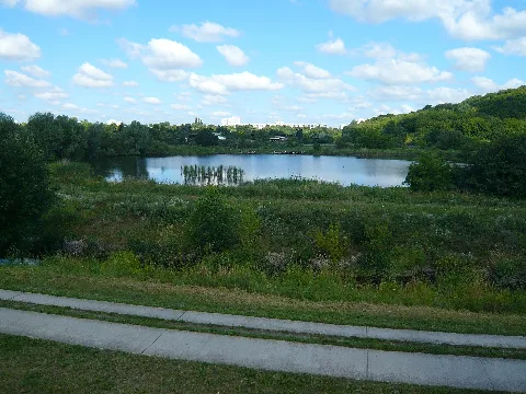 Berlin-Marzahn-Hellersdorf, Rohrbruch(park). Mittlerweile wurde dieser Bereich zur IGA 2017, mit Teilen der Umgebung zum Kienbergpark zusammengefasst. Der Blick geht von oberhalb des Wuhletal-Wanderweges auf den Wuhleteich, einem in den 1980'er Jahren künstlich angelegtem Gewässer, welches von der Wuhle durchflossen wird. Die Anlage erfolgte ursprünglich auch für eine Gartenschau. An der Hinterkante, dem nord-westlichen Bereich, ist noch die gerade gut belagerte Betonkanteneinfassung zu sehen. Diese wurde im Zusammenhang der Umgestalltungen für die IGA 2017 entfernt und weiter rechts hinüber zum Zufluß des Biesdorf-Marzahner Grenzgrabens hin, eine neue, breitere Terasse mit dem Umweltbildungszentrum errichtet. Im Vordergrund, gleich hinter dem Weg, verläuft der gerade gut mit Wasser gefüllte Graben der 'Neuen Wuhle'. Hier beim Wuhleteich, stoßen die Ortsteile Biesdorf (linker Bereich hinter dem Teich), Hellersdorf (Kamerastandort und im Rücken des Betrachters) und Marzahn (Rechts beim Kienberg) zusammen.